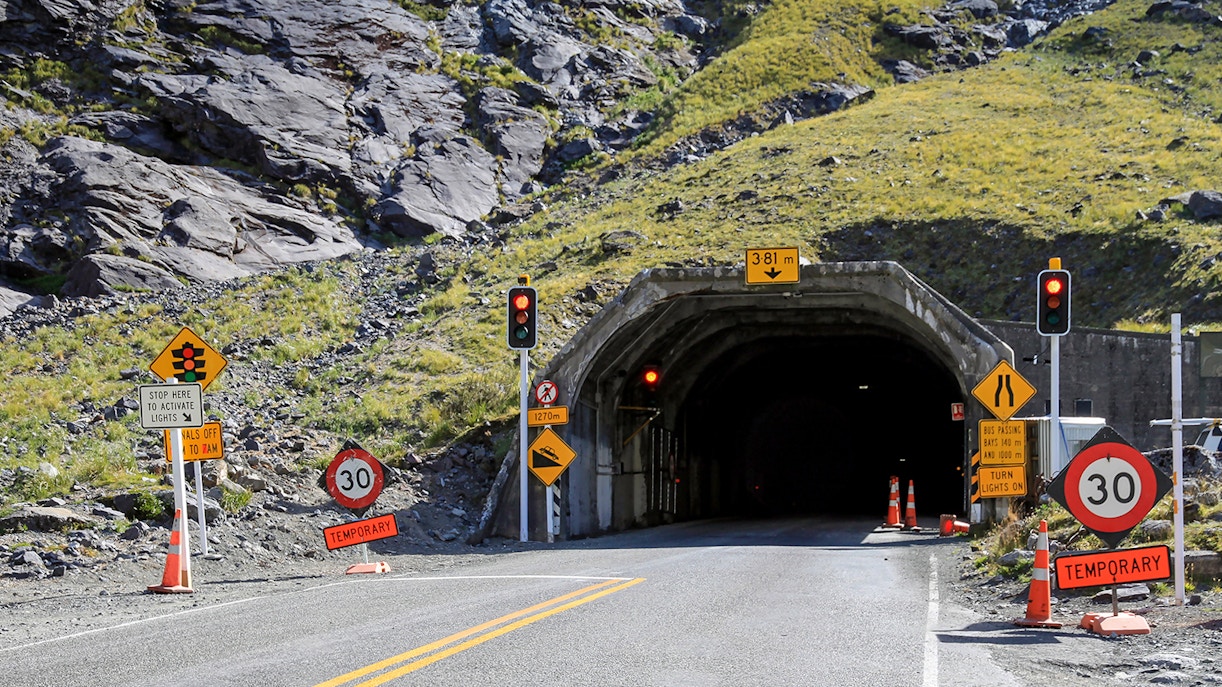 Homer Tunnel entrance in Fiordland National Park, New Zealand, surrounded by lush mountains.