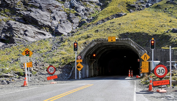 Homer Tunnel entrance in Fiordland National Park, New Zealand, surrounded by lush mountains.
