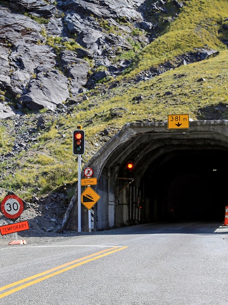 Entrance to Homer Tunnel with traffic signs on the road to Milford Sound, Fiordland National Park, New Zealand.