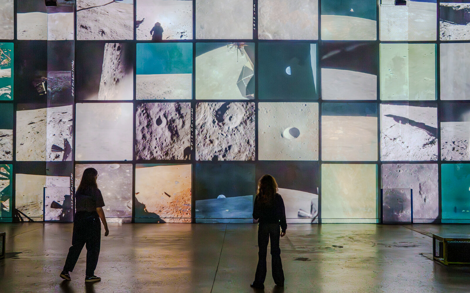 Visitors viewing lunar surface projections at The Moonwalkers Exhibition, Atelier des Lumières.
