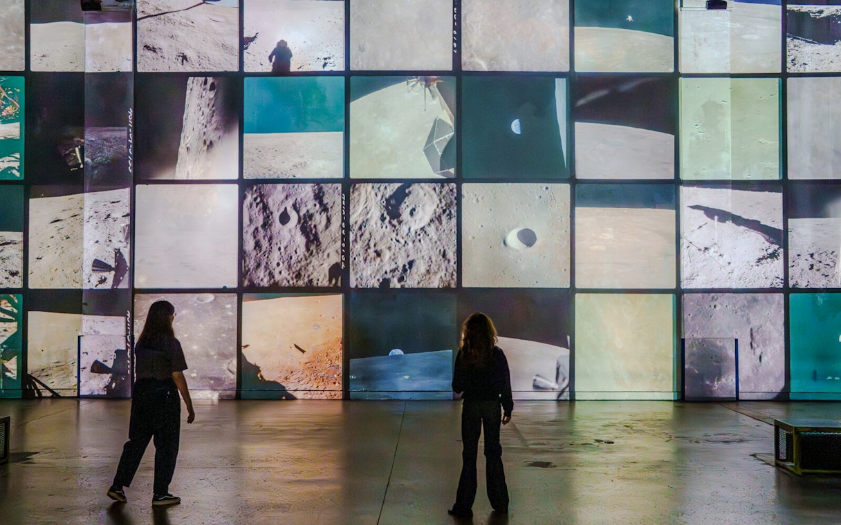 Visitors viewing lunar surface projections at The Moonwalkers Exhibition, Atelier des Lumières.