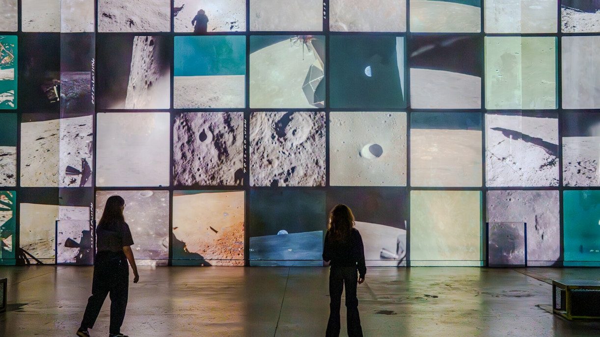 People viewing digital art projection at Atelier des Lumières, Paris, featuring surreal imagery.