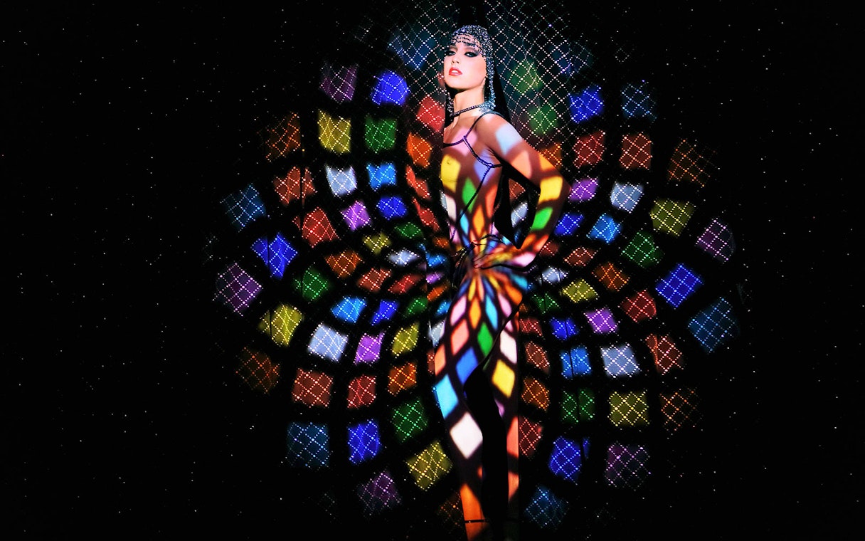 Performer at Crazy Horse Show with colorful light patterns in Paris.