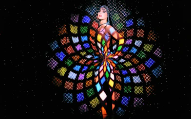 Performer at Crazy Horse Show with colorful light patterns in Paris.