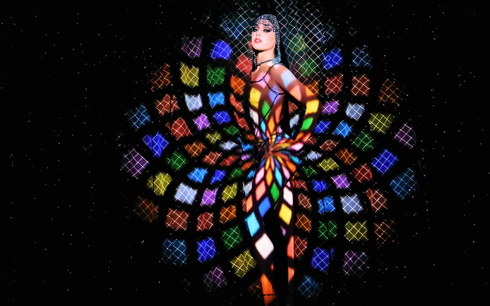 Performer at Crazy Horse Show with colorful light patterns in Paris.