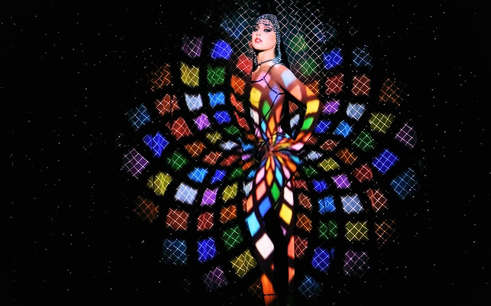 Performer at Crazy Horse Show with colorful light patterns in Paris.