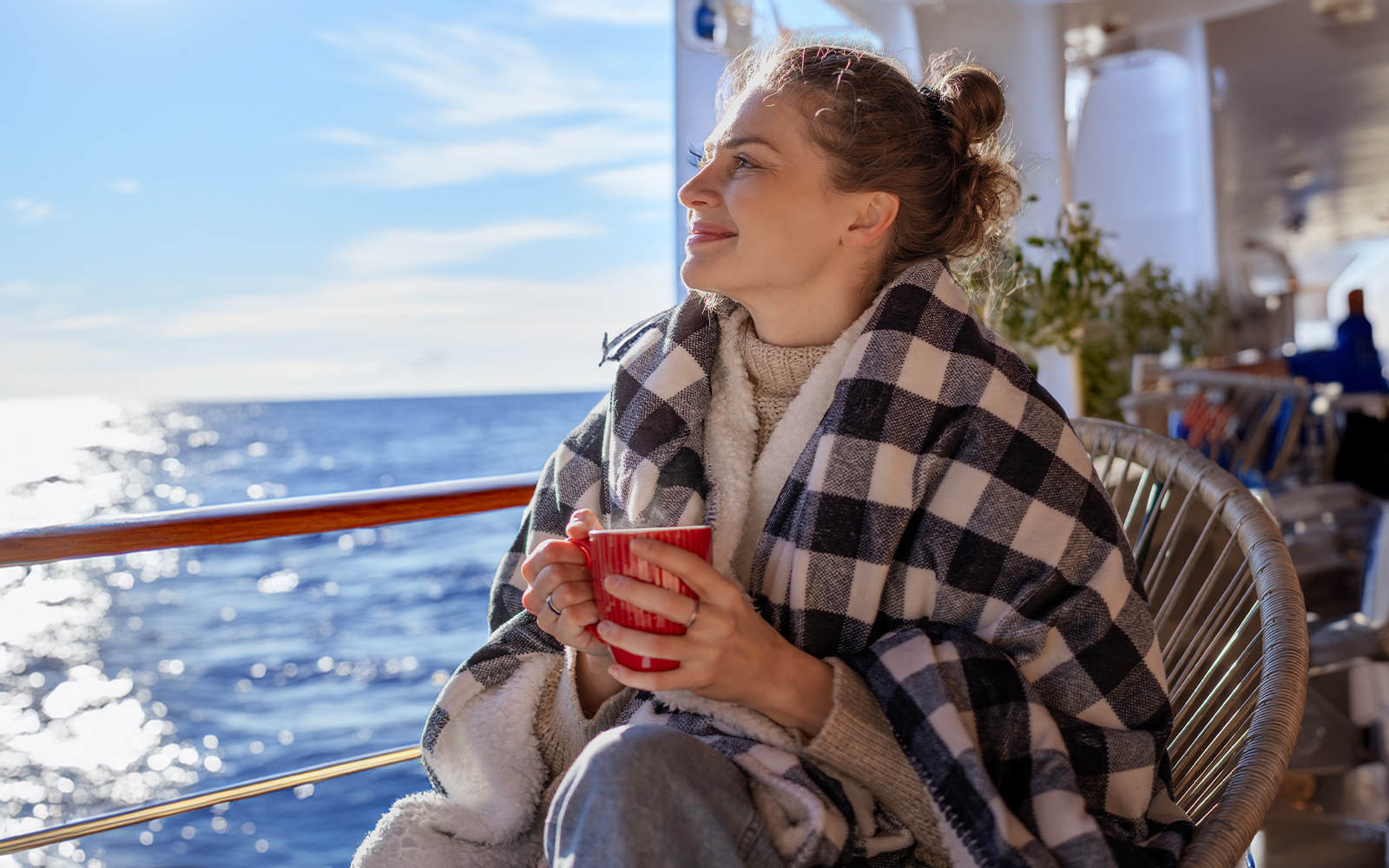 A woman in a blanket sitting on the deck of a cruise