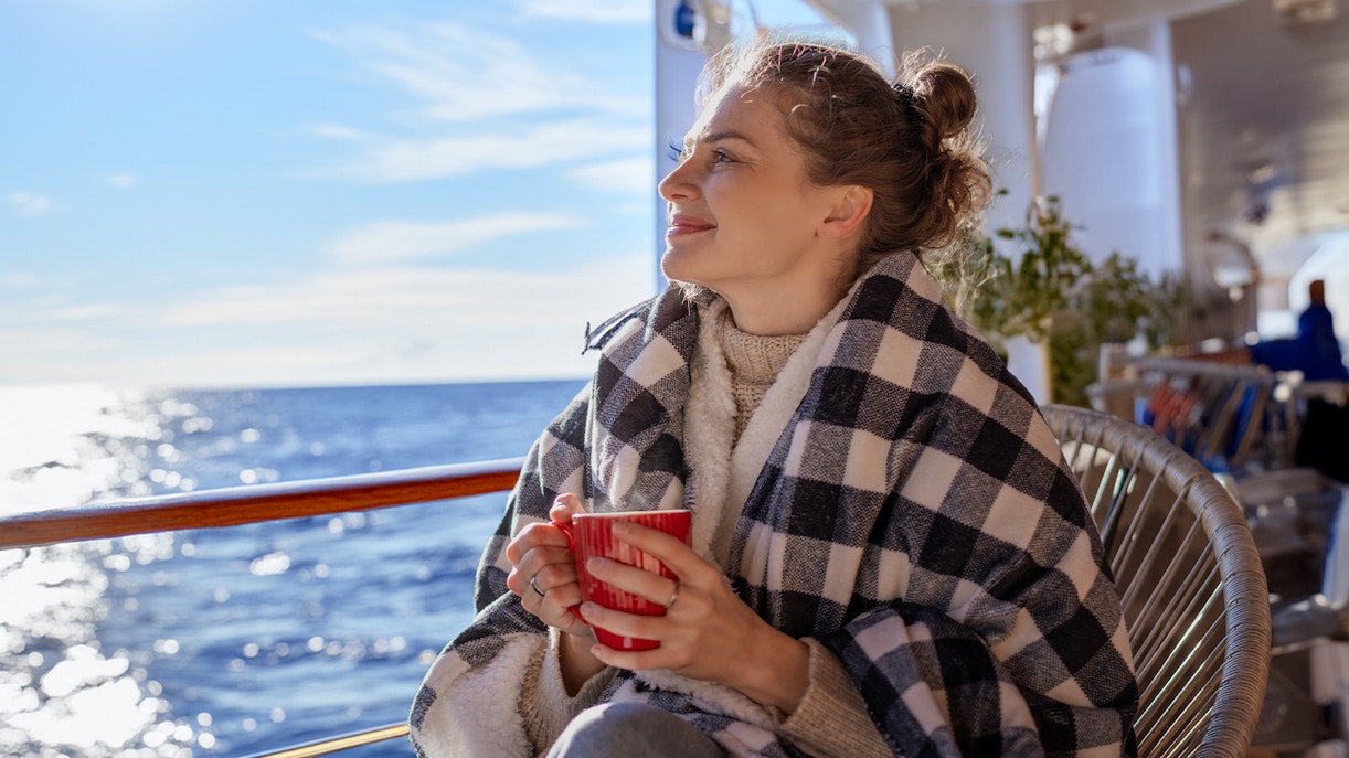 A woman in a blanket sitting on the deck of a cruise