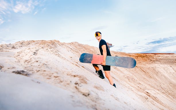 Snowboarder sand boarding on a dune in Australia.