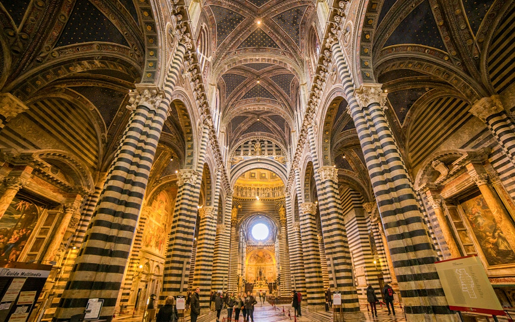 Siena Cathedral interior with striped columns and ornate ceiling.