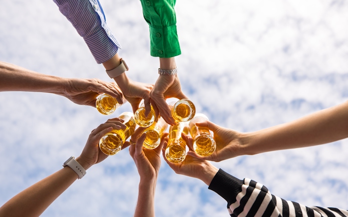 Group toasting with beer glasses under a blue sky at Heineken rooftop experience.