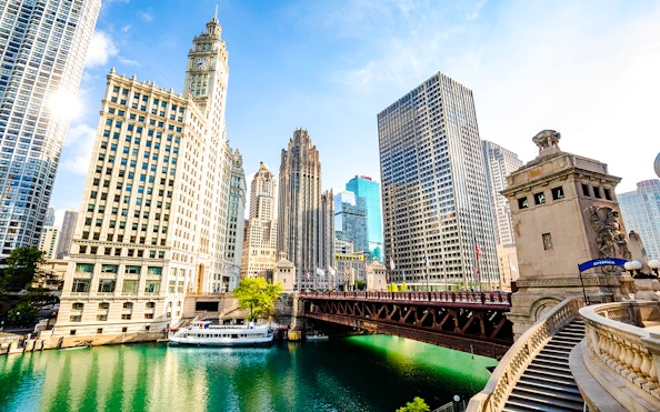 Chicago River with skyscrapers and a tour boat near the Wrigley Building and DuSable Bridge.