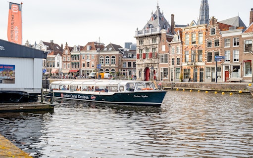 Canal cruise boat on Haarlem waterway with historic buildings in the background.
