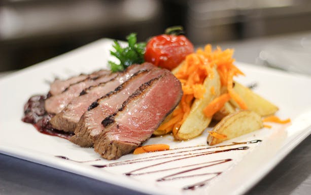 Sliced steak with roasted potatoes and carrots on Budapest Danube River Candlelit Dinner Cruise.