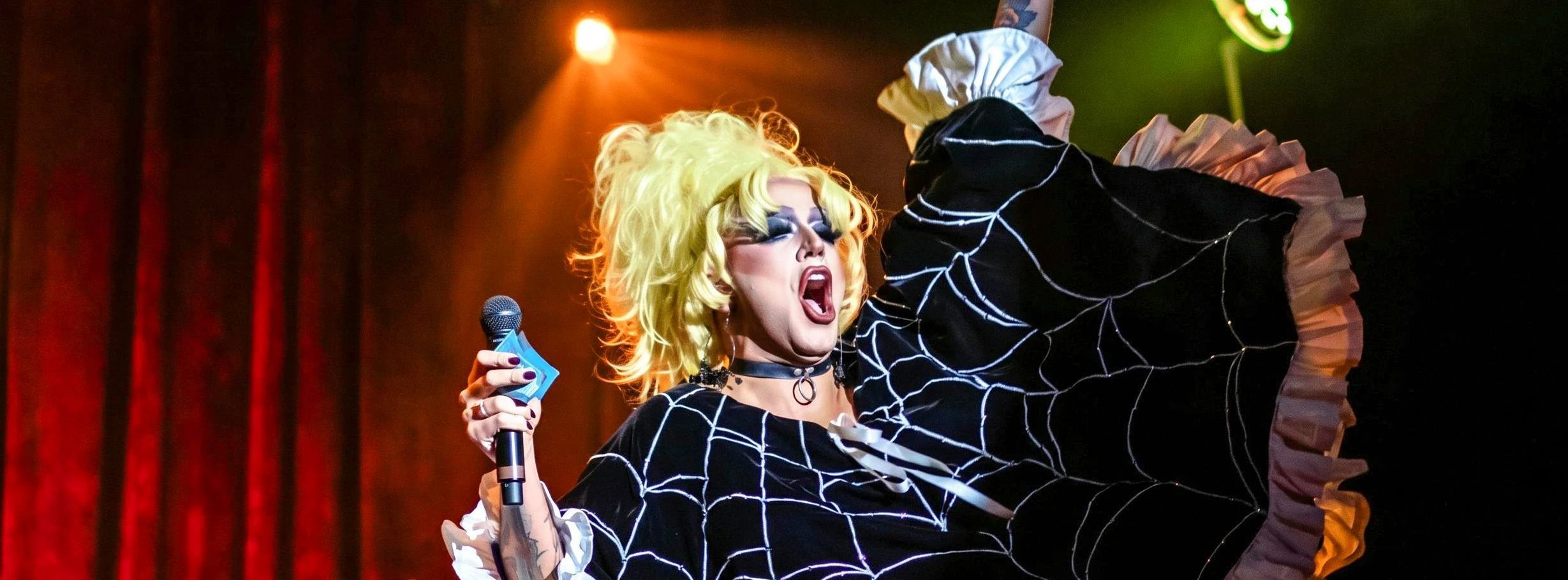 Performer on stage at Madame Arthur cabaret show with audience reaching up.