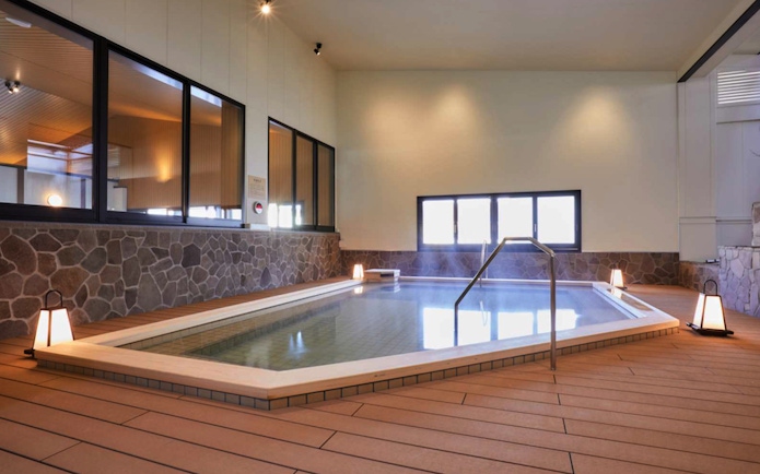 Indoor hot spring bath at Solaniwa Onsen, Osaka, with stone walls and ambient lighting.