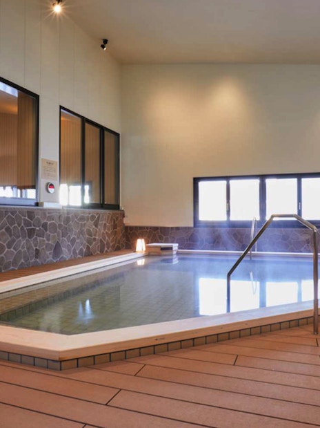 Indoor hot spring bath at Solaniwa Onsen, Osaka, with stone walls and ambient lighting.