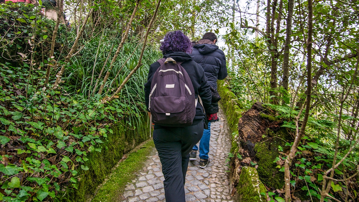 Visitors walking through lush gardens at Quinta da Regaleira, Sintra, Portugal.