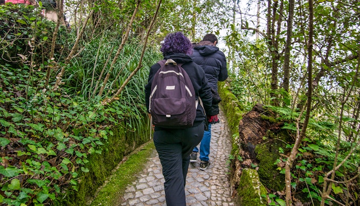 Visitors walking through lush gardens at Quinta da Regaleira, Sintra, Portugal.