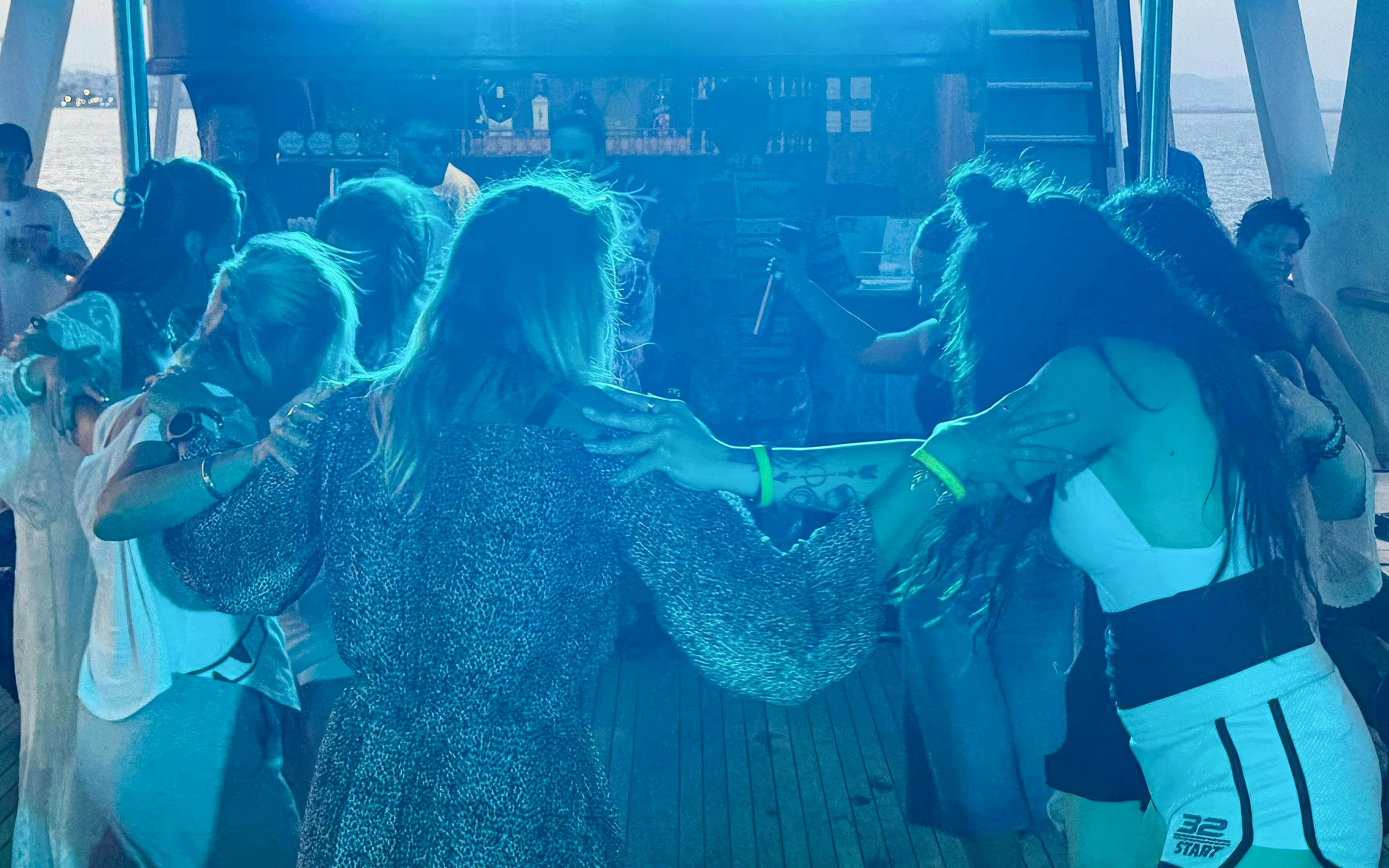 Group dancing on a sunset cruise from Larnaca with blue lighting.