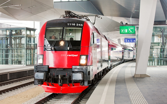 Red ÖBB Railjet train at a modern station platform, part of the Eurail Global Flexible Pass experience.