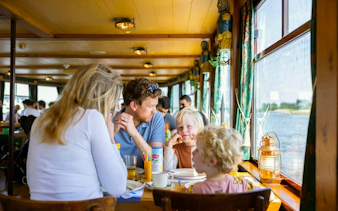 Family enjoying Dutch pancake cruise on a boat in Amsterdam.