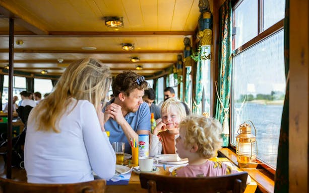 Family enjoying Dutch pancake cruise on a boat in Amsterdam.