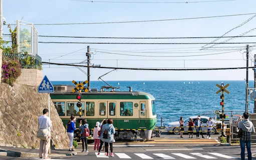 Train crossing near the sea on the Enoden line in Japan.