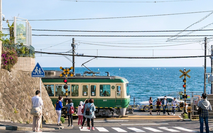 Train crossing near the sea on the Enoden line in Japan.