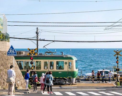Train crossing near the sea on the Enoden line in Japan.