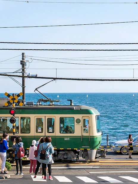 Train crossing near the sea on the Enoden line in Japan.