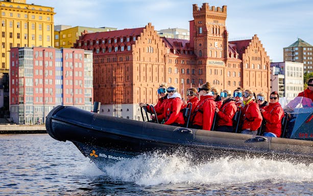 Passengers on a RIB speed boat tour in Stockholm with historic buildings in the background.