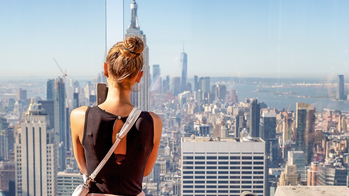 Female tourist viewing Manhattan skyline from Rockefeller Center's Top of the Rock, New York City.