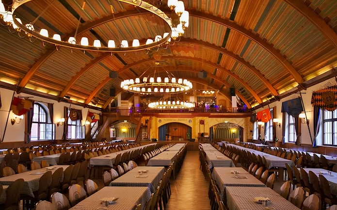 Hofbräuhaus beer hall interior with long tables and chandeliers in Munich, Germany.