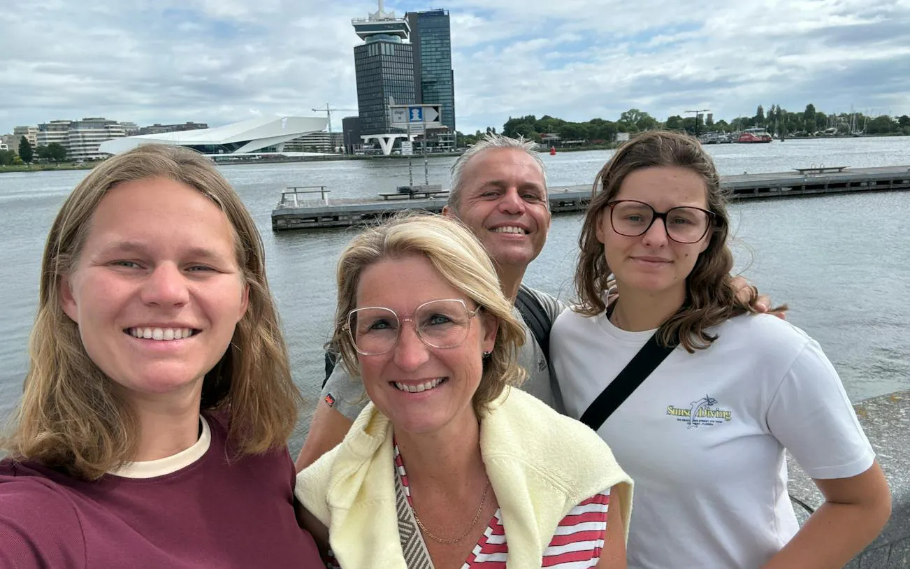Group enjoying Amsterdam waterfront with A'DAM Tower in the background.