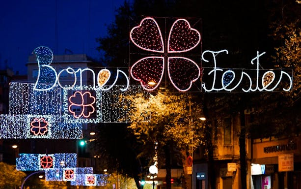 Barcelona street with festive Christmas lights and "Bones Festes" sign.