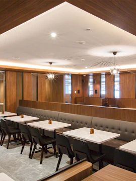 Seating area in Plaza Premium Lounge, Melbourne with modern decor and tables.