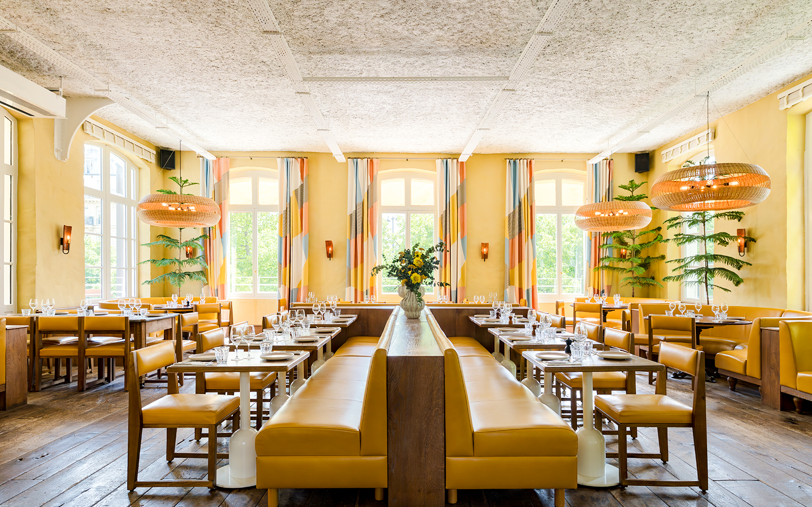 Interior of Brasserie Auteuil with yellow seating, wooden tables, and large windows.