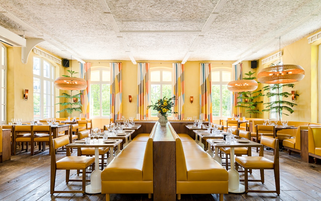 Interior of Brasserie Auteuil with yellow seating, wooden tables, and large windows.