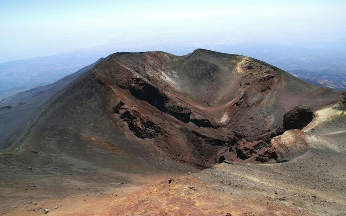 Crater of Mount Etna in Sicily with surrounding volcanic landscape.