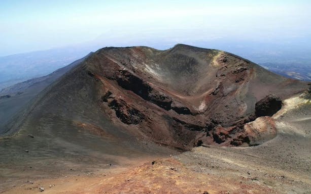 Crater of Mount Etna in Sicily with surrounding volcanic landscape.