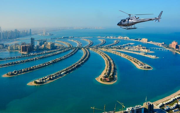 Helicopter flying over Palm Jumeirah, Dubai, showcasing the iconic palm-shaped islands.