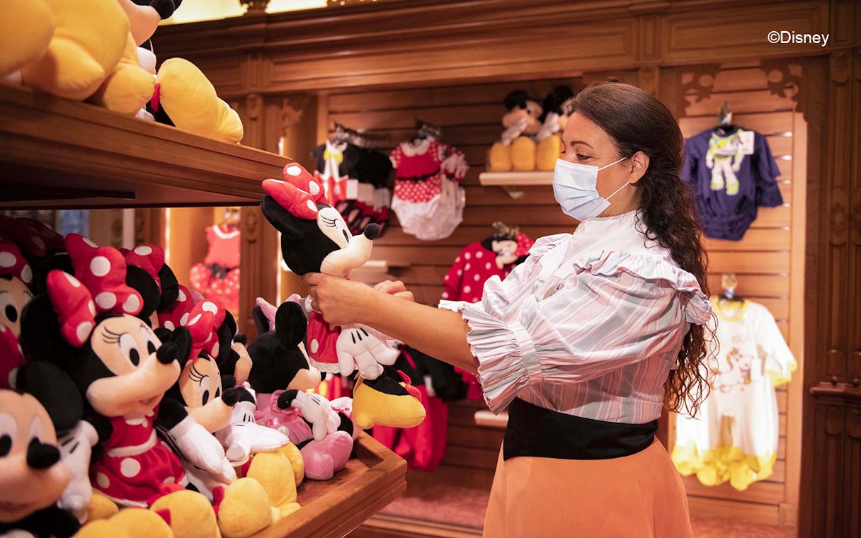 Woman shopping for Minnie Mouse plush toys at Disneyland Paris store.