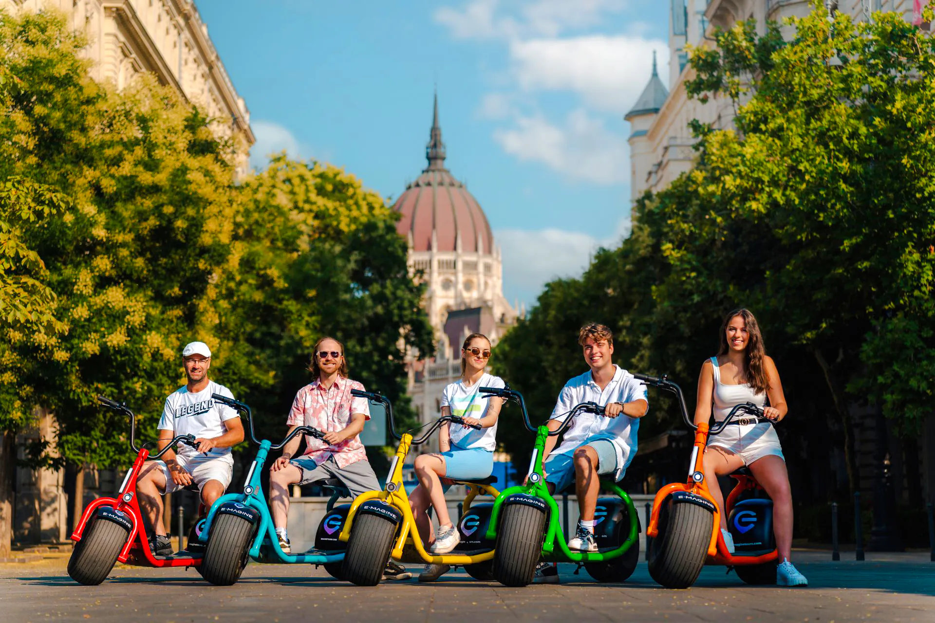 Group riding e-scooters in front of the Hungarian Parliament Building, Budapest.
