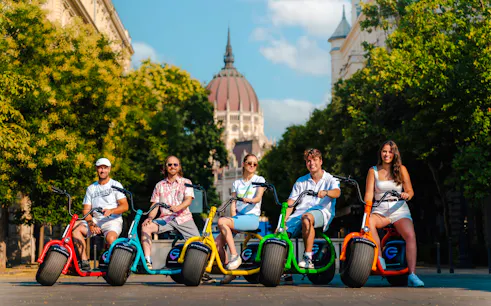 Group riding e-scooters in front of the Hungarian Parliament Building, Budapest.