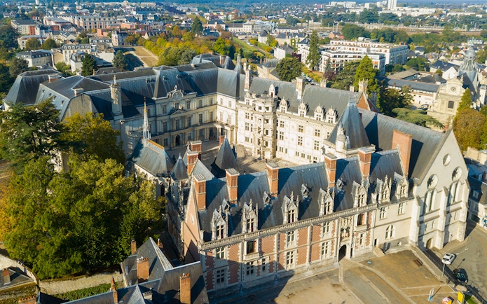 Aerial view of Blois Castle in France, showcasing its Renaissance architecture and surrounding town.