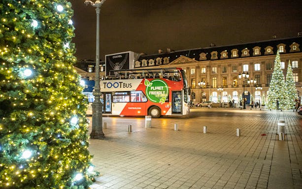 Tootbus at night in a festive city square with illuminated trees.