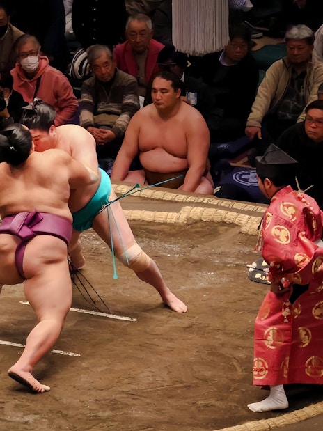 Sumo wrestlers grappling in a traditional ring during a match in Japan.