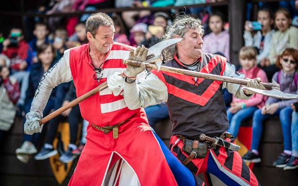 Performers in medieval costumes engaging in combat during the Medieval Show in Visegrád.