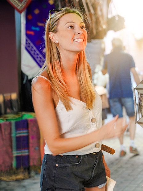 Tourist exploring lanterns in Marrakesh Medina souks during guided walking tour.